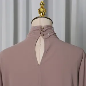Back view detail of mauve high neck top with rhinestone ruffled collar and button closure
