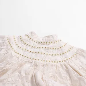 Close-up of elegant white lace dress detail with high collar, embroidery and pearl buttons
