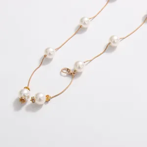 Detail shot of elegant gold snake chain with white pearls and rhinestone accents.