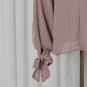 Elegant mauve long sleeve top detail featuring a stylish bow-tie cuff and rhinestone accents.
