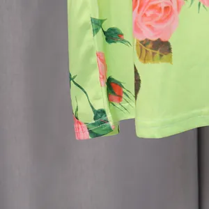 Close-up detail of vintage lime green floral dress with pink rose print and neat stitching