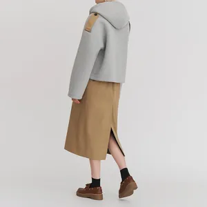 Rückansicht einer grauen Kapuzenjacke kombiniert mit einem khakifarbenen Midi-Rock