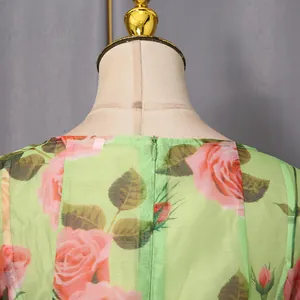 Close-up detail of the rose floral print and hidden back zipper on a green dress.