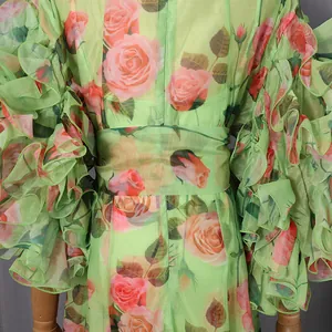 Close-up detail showing the vintage pink rose floral print on a green chiffon dress with ruffles