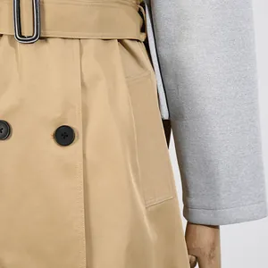 Detailansicht eines beigefarbenen Trenchcoats mit grauen Ärmeln und Gürteltaille