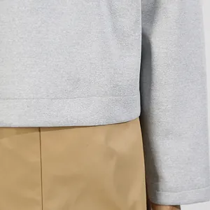 Nahaufnahme von grauem Strukturstoff und khakifarbenem Saum an einer Freizeitjacke