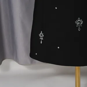 Primer plano de los brillantes motivos florales de strass en un vestido de noche negro.