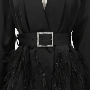 Detailansicht des schwarzen Blazer-Kleides mit Kristallschnallengürtel und Federsaum.