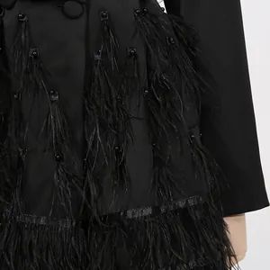 Nahaufnahme eines schwarzen Blazer-Kleids mit eleganten Federverzierungen und Perlen