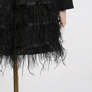 Nahaufnahme der schwarzen Straußenfedern am Saum eines eleganten Blazer-Kleides