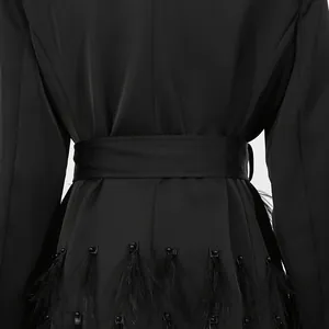 Detailansicht des schwarzen Blazer-Kleides mit elegantem Federbesatz und Taillengürtel.