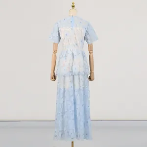 Vista trasera de un vestido largo de malla bordada azul claro en un maniquí de madera