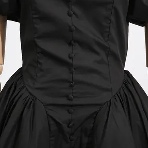 Close-up of a black French style dress featuring elegant waist buttons and pleated details