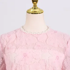 Primer plano detallado del vestido de malla bordada rosa con detalle de perlas al cuello