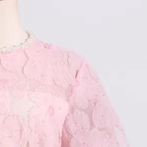 Primer plano de vestido de malla rosa con apliques florales y cuello de perlas