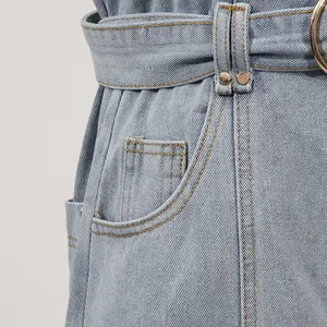 Detailaufnahme der Taille eines hellblauen Jeanskleides mit Gürtelschnalle und Taschendetail