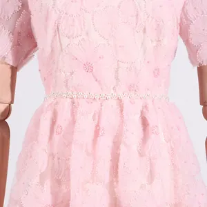 Primer plano de vestido de malla rosa con bordado floral 3D y detalle de perlas