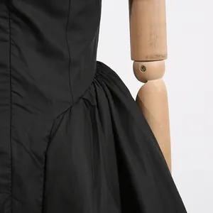 Close-up of the elegant pleated waist detail on a black French style high-waisted dress