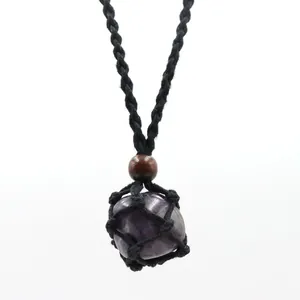 Detail of raw amethyst stone necklace pendant wrapped in handmade black woven net