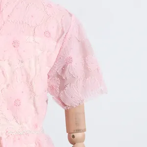 Detalle de cerca de vestido rosa estilo francés con delicados bordados de flores y cuentas