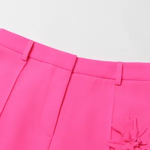 Detalle de cerca de pantalones de blazer rosa fucsia con aplique de flor 3D chic
