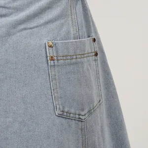 Detailaufnahme der Tasche eines hellblauen Jeanskleids mit Kupfernieten und Nähten