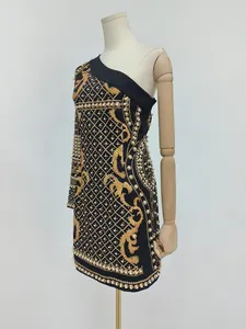 Detail view of French retro one-shoulder mini dress with gold print and pearl beading.