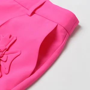 Detalle de cerca de una chaqueta rosa brillante con apliques de flores 3D y bolsillo