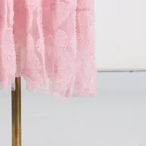 Detalle de primer plano de tela de malla rosa con bordado floral y cuentas en un vestido