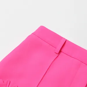 Primer plano de un blazer rosa con una elegante aplicación floral 3D en el detalle.