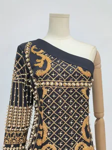 Close-up of elegant one-shoulder vintage dress with golden print and pearl details