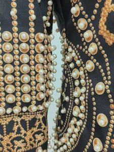 Close-up detail of luxury French retro dress with gold print and pearl beading