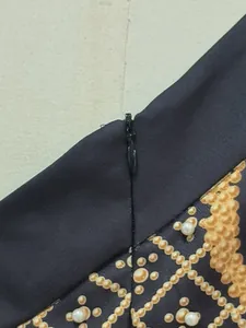 Detailed view of the invisible zipper and pearl embellishments on a vintage printed dress.