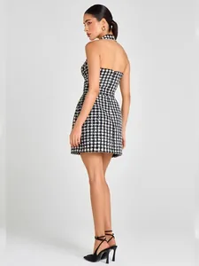 Vista lateral de un elegante minivestido halter de tweed con lentejuelas en blanco y negro