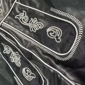 Detail of white embroidery and piping on traditional black leather Oktoberfest pants.