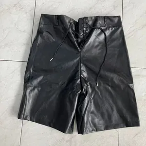 Detailed texture of black synthetic leather shorts with front lace-up closure detail