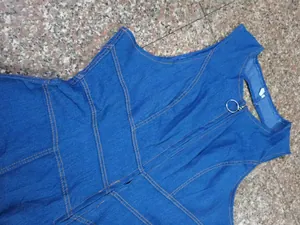 Detail of yellow contrast stitching and ring zipper on blue denim sleeveless jumpsuit