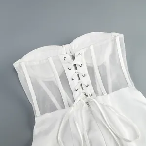 Dettaglio dell'abito a corsetto in rete bianca con struttura a stecche e stringatura