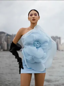 Detailed view of light blue one-shoulder party dress with large 3D fabric flower