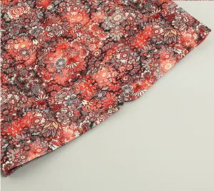 Close-up detail showing the intricate red floral and paisley fabric pattern on elegant dress