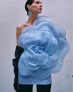 Elegant detail of a large 3D fabric flower on a light blue one-shoulder party dress.
