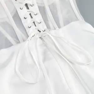Dettaglio di un abito a corsetto bianco con lacci sulla schiena e pannelli in rete