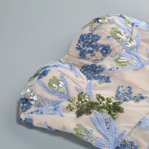 Gros plan détaillé montrant des broderies florales et des paillettes sur une robe de fête