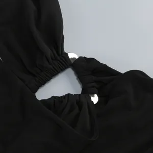 Detailed view of the polished silver triangle ring and pleated fabric on the black halter dress.