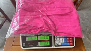 Fuchsia pleated summer dress being weighed on a digital scale showing 0.330 kg