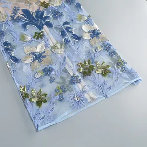 Détail de la broderie florale bleue et des paillettes brillantes sur la robe de soirée
