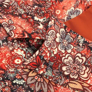 High-resolution close-up of elegant red floral paisley print on woman's jacket.