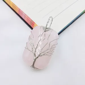 Macro detail of handmade silver wire-wrapped tree of life design on pink crystal