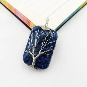 Detail of hand-wrapped silver wire tree of life on a rectangular blue gemstone pendant