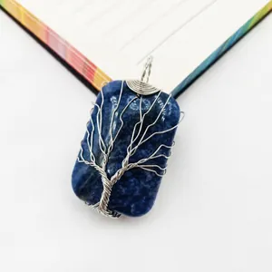 Detalle del árbol de la vida envuelto en alambre sobre colgante de gema azul rectangular